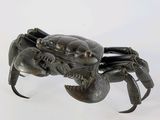 un crabe en métal posé sur une surface blanche