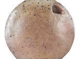 un vase brun posé sur une surface blanche