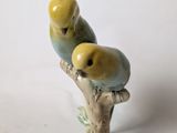 two figurines of birds sitting on a tree branch