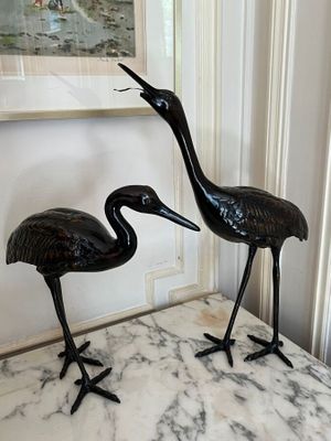 two statues of two birds on a marble table