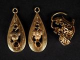 trois bijoux en or posés sur une surface noire