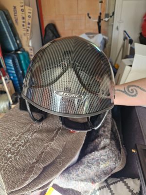a person holding a motorcycle helmet on top of a pile of clothing