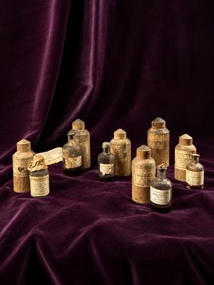 several old bottles are lined up on a purple cloth