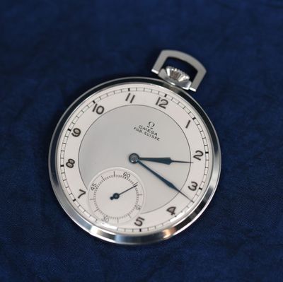 un gros plan d'une montre de poche posée sur un tissu bleu
