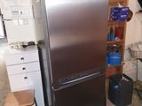 a silver refrigerator in a room with a table and chairs