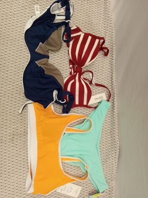 plusieurs maillots de bain étalés sur un lit dans une chambre