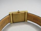 a gold watch on a brown leather band