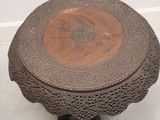 a wooden table with a carved top on a white floor