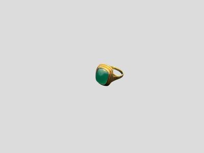 a close up of a gold ring with a green stone