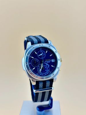 la montre est posée sur un présentoir et est dotée d'un bracelet bleu et noir