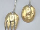 pair of silver and gold plated spoons on a white surface