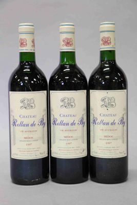 trois bouteilles de vin rouge sont alignées sur une surface blanche