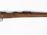 un vieux fusil avec un canon en bois sur une surface blanche