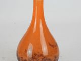 an orange glass vase sitting on a white surface
