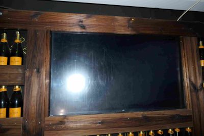 une télévision accrochée au mur, à côté de bouteilles de vin