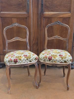 pair of antique chairs with floral upholstered seats in front of wooden doors