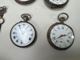 several different types of pocket watches are displayed on a table