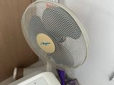 a fan sitting next to a washing machine in a room