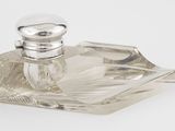 une petite bouteille en verre avec un bouchon argenté, posée sur un plateau