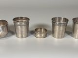 quatre coupes en argent sont alignées sur une surface blanche