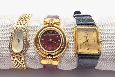 Trois montres-bracelets pour femmes sont posées sur un tissu blanc