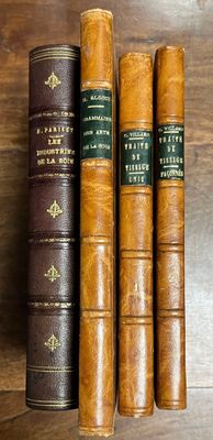 three old books on a wooden table, one of which is brown and one of which is green