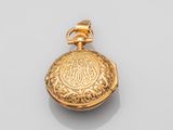 a close up of a gold pocket watch on a white surface