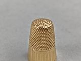 a close up of a gold thimble on a white surface