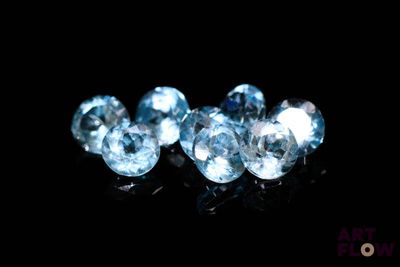 un gros plan sur trois diamants de couleur topaze bleue posés sur une surface noire
