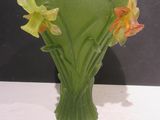 un vase vert avec des fleurs jaunes à l'intérieur, posé sur une table