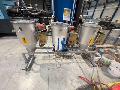 trois cuves en acier inoxydable posées sur une table dans un entrepôt