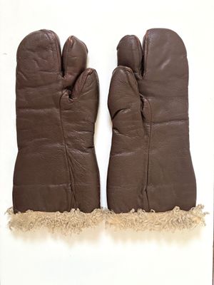 une paire de mitaines en cuir marron posées sur une surface blanche, sur fond blanc