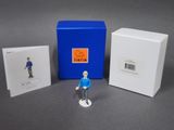 a small figurine of a man standing next to a blue box