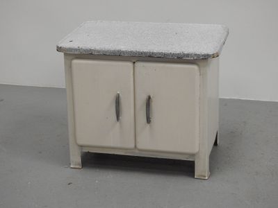 une petite armoire blanche avec un plan de travail en granit, posée sur un sol gris