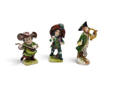 three figurines of a man playing a trumpet, a woman playing a trumpet, and a man playing a trumpet