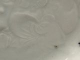 une assiette blanche sur laquelle figurent un oiseau et un insecte