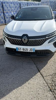 une voiture blanche garée sur un parking près d'une clôture
