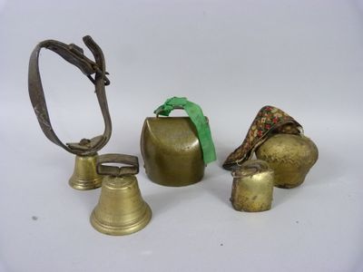 trois clochettes en laiton et un anneau posés sur une surface blanche