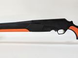 un fusil noir muni d'une poignée orange, posé sur un socle transparent