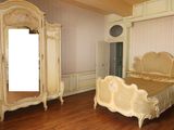 une chambre avec un lit, des commodes et un miroir