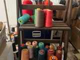 many spools of thread sitting on a shelf in a room