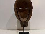 sculpture of a wooden mask on a stand on a white surface