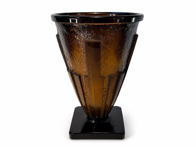 un vase en verre brun avec un socle noir sur fond blanc