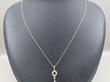 a gold necklace with a diamond key on a mannequin neck