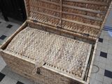 a wicker box with a lid open on a tiled floor