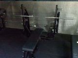 une salle de sport avec un banc, des poids et d'autres équipements