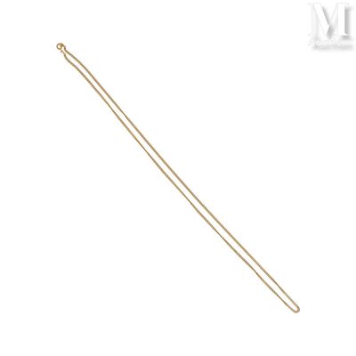 un gros plan d'un collier en or à longue chaîne sur fond blanc
