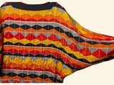 a woman that is holding a colorful blanket on her back
