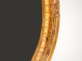a close up of a gold oval mirror with a black background