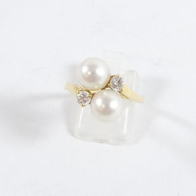 un gros plan d'une bague ornée de deux perles sur un fond blanc